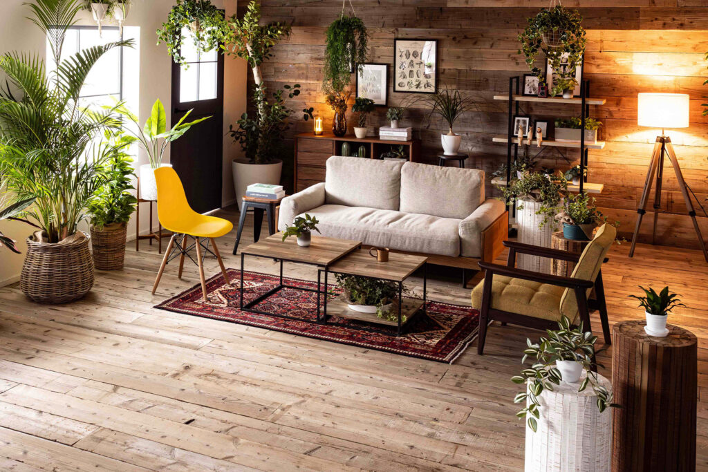ヴィンテージウッドの壁と床の部屋にソファと椅子、植物が配置されています。