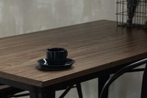 木目調のテーブルの上に置かれた、黒いティーカップの写真
