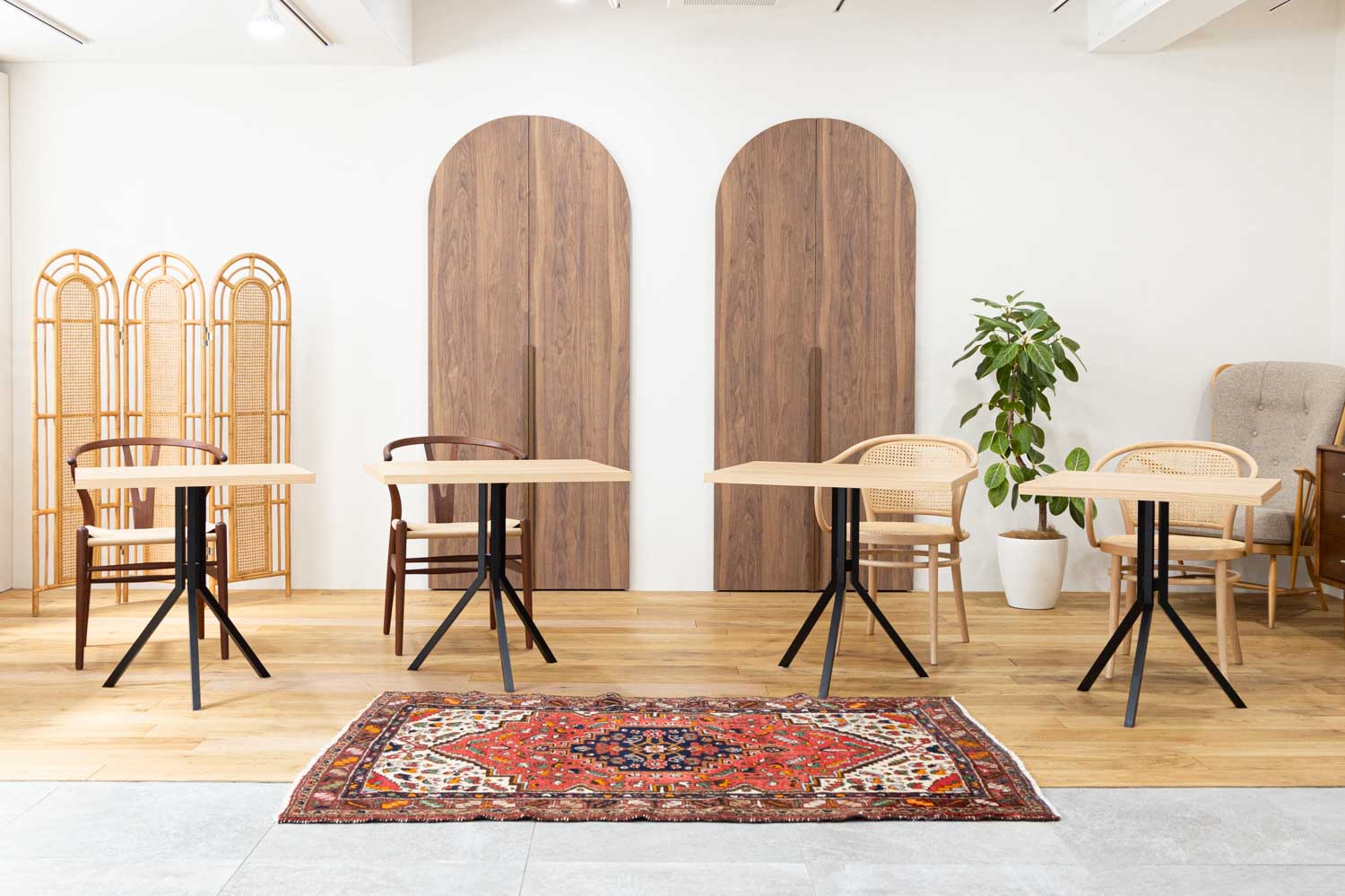木製ドア2枚の前に、テーブルと椅子のセットが4つ配置された写真