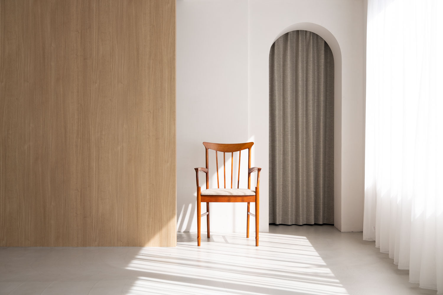 アーチ壁がある明るい空間に、木製の椅子が置かれた写真