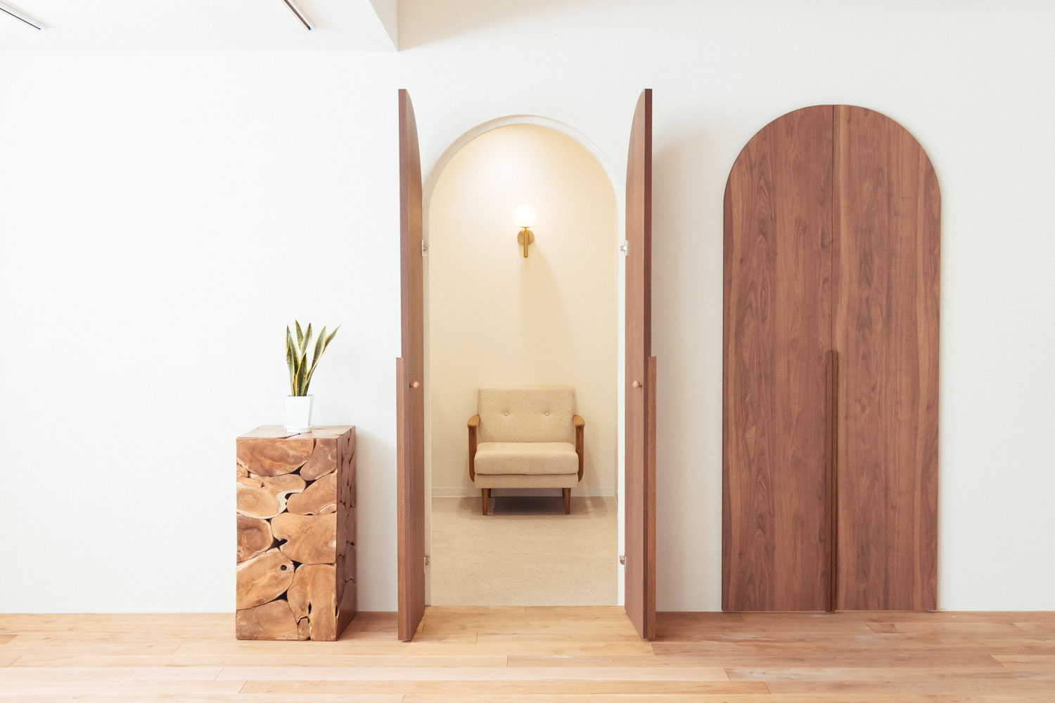 円形の木製ドアが開いた奥に、一人掛けソファが照明に照らされている写真