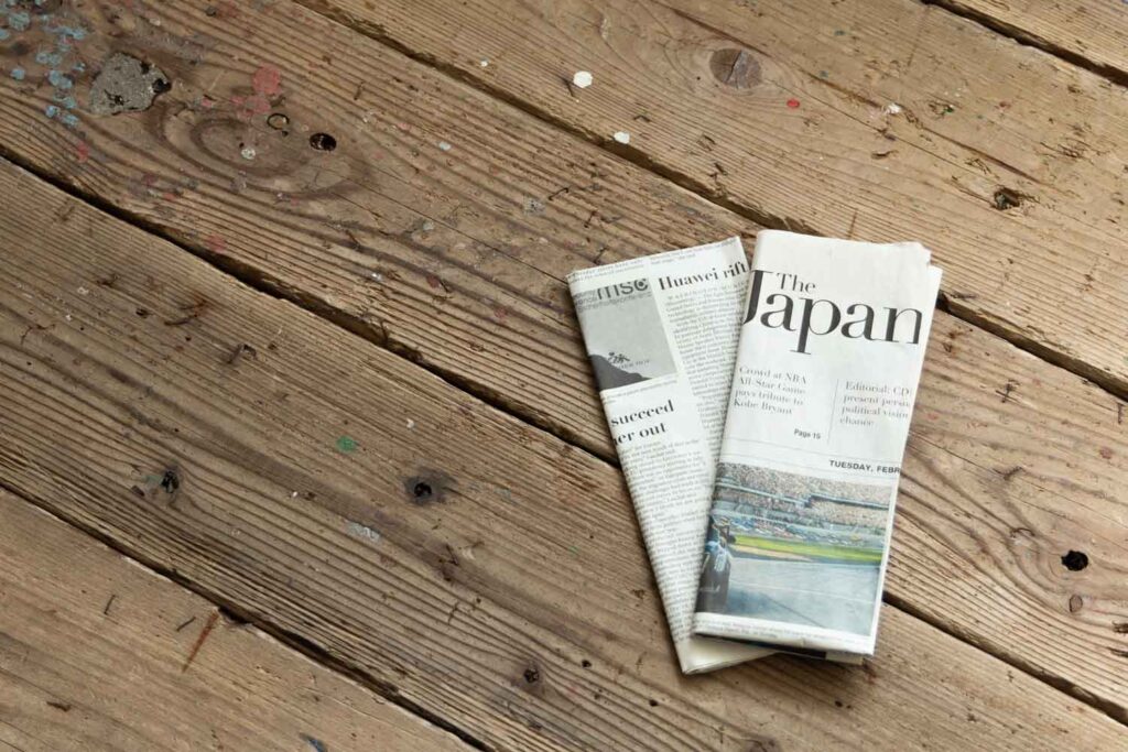 ウッド調の床に、折りたたんだ英字新聞が2枚置かれている写真