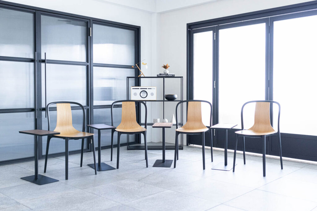 黒いフレームドアがある空間に、一人用の椅子とテーブルが4セット並ぶ写真