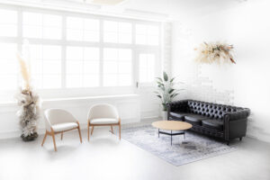 白いラウンジチェアと黒いソファーが白いスタジオの中に設置してある写真