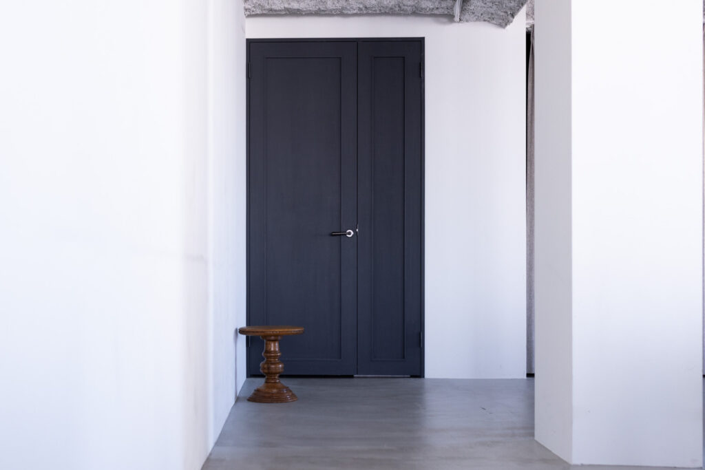 白基調の空間奥にある、大きいダークブルーのドア