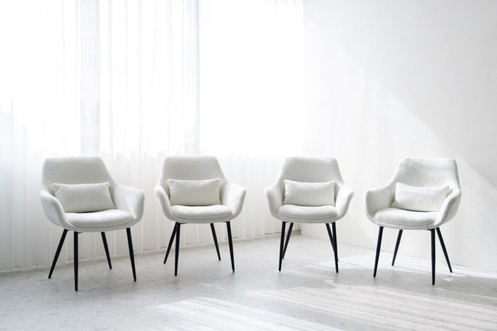 自然光が入る窓際に、白い椅子が4つ並んでいる写真
