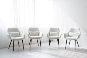 自然光が入る窓際に、白い椅子が4つ並んでいる写真