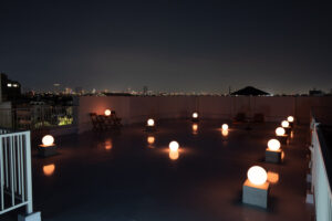 夜間の屋上で、夜景を背景にライティングボールがオレンジに光る写真