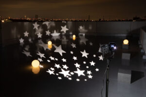 夜間の屋上を、ライトプロジェクターが照らす写真