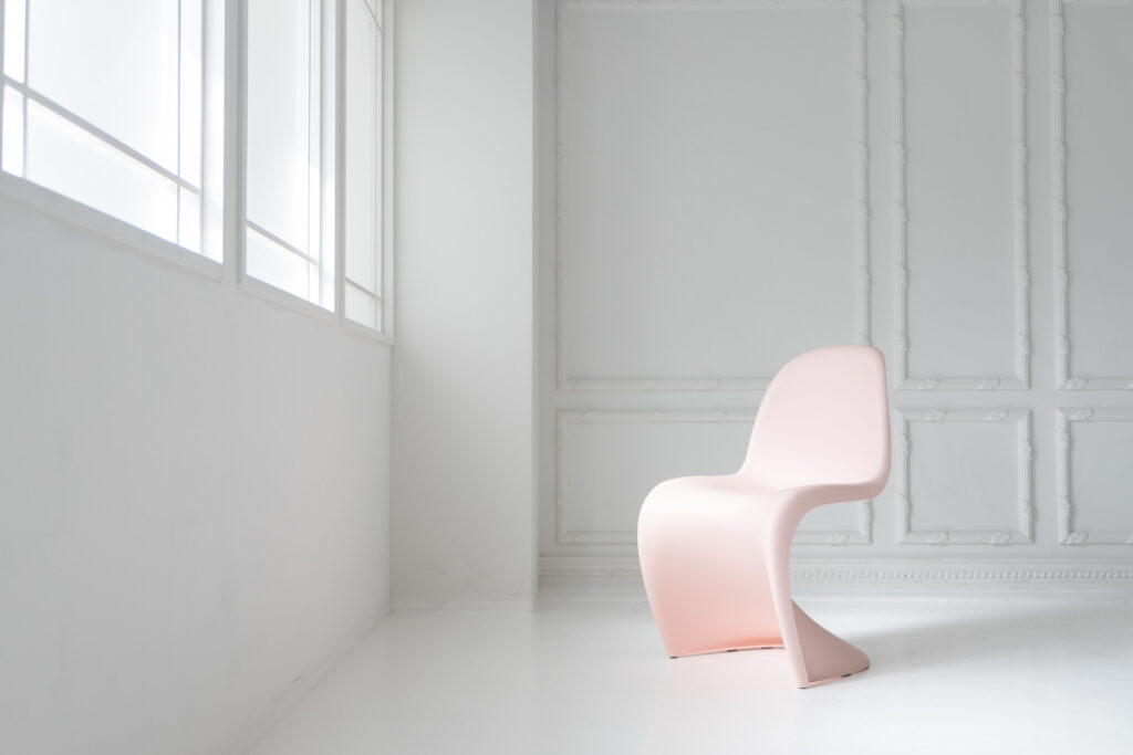 白基調の自然光あふれるスペースに、ピンクの椅子が配置された写真