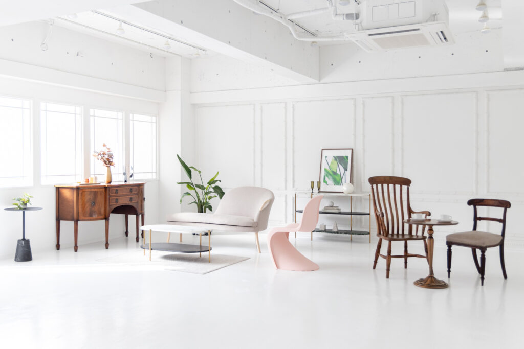 白基調の広いスペースに、キャビネット・椅子など家具が配置されている写真