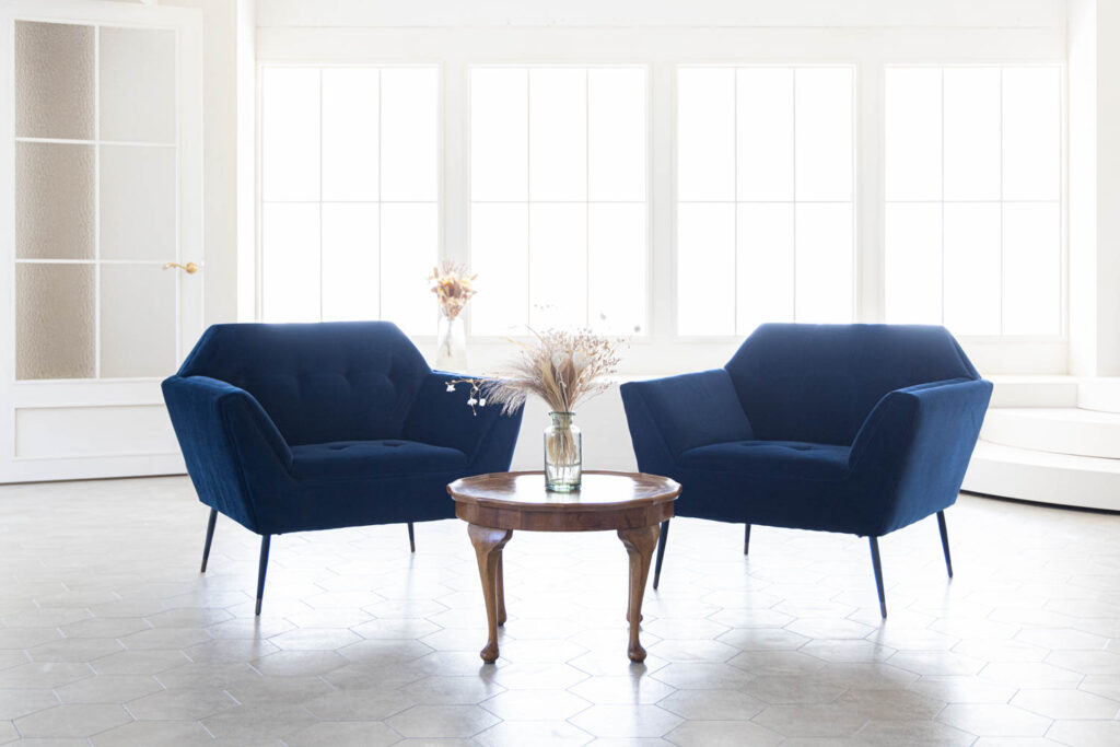 格子窓から自然光が入る白基調の空間に、青いソファが対談風に配置された写真